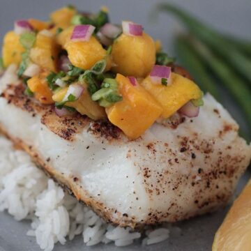 Chilean sea bass with mango salsa and rice on a plate.