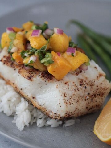 Chilean sea bass with mango salsa and rice on a plate.