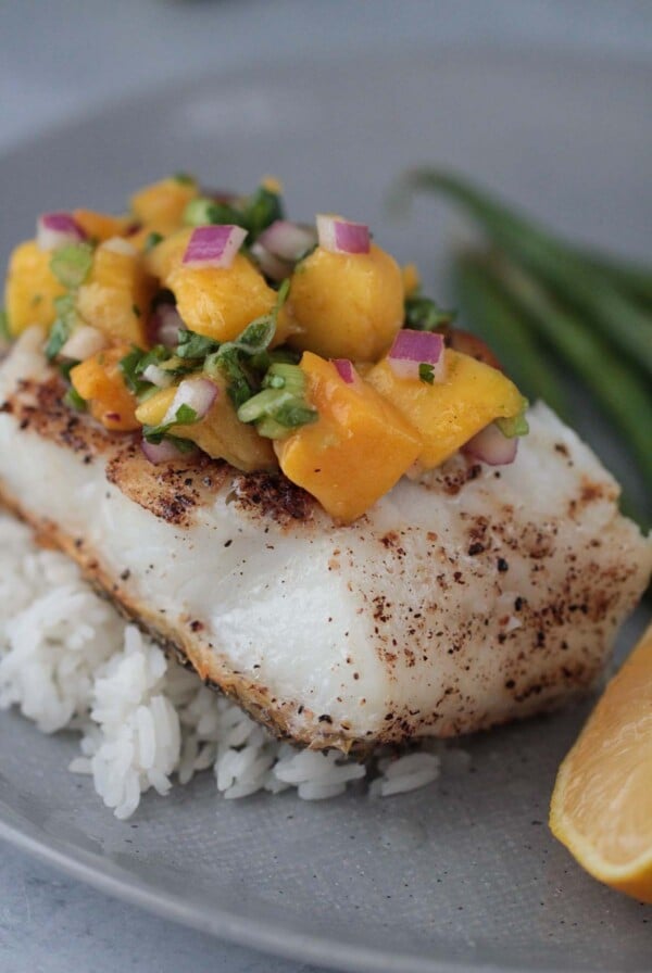 Chilean sea bass with mango salsa and rice on a plate.