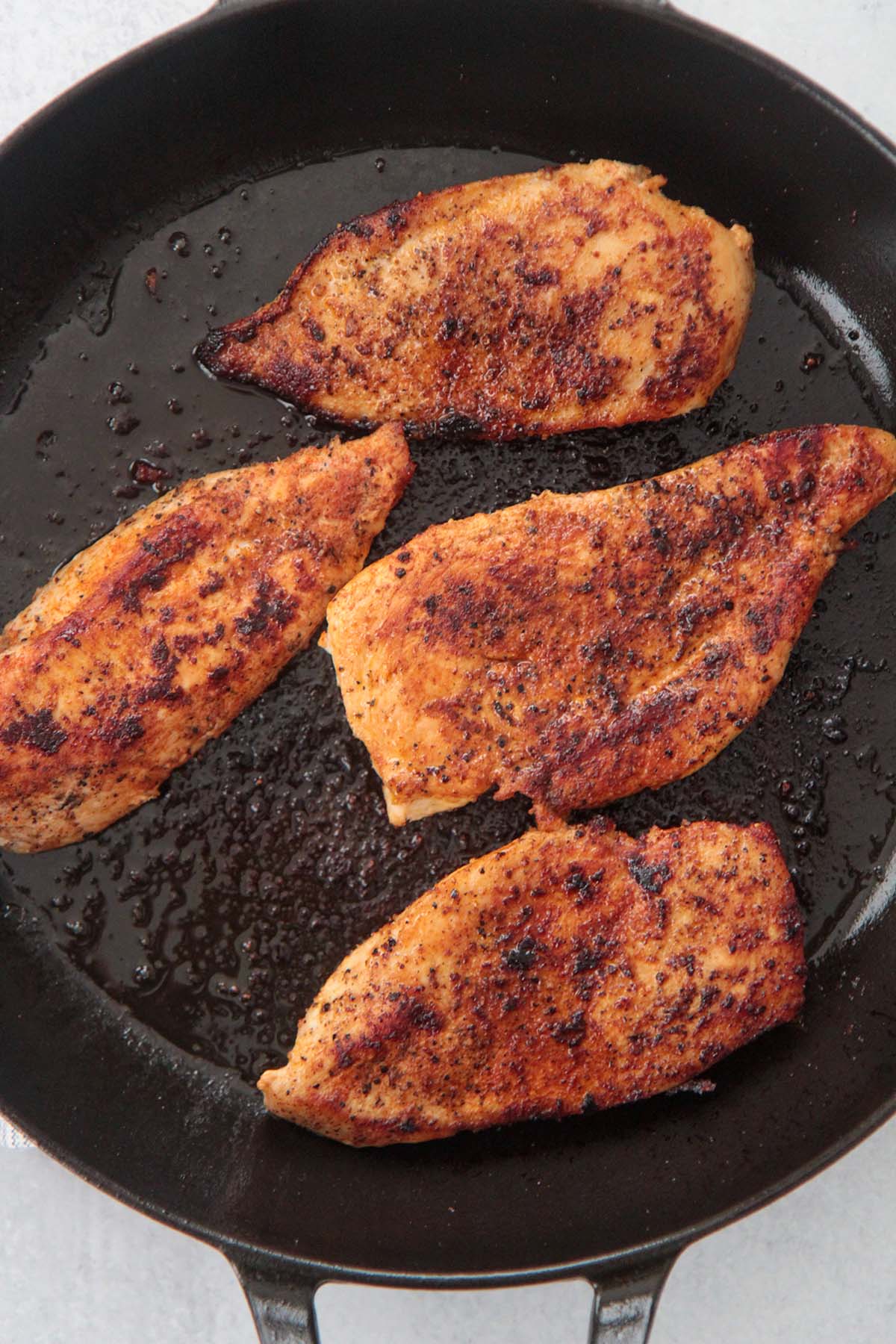 4 cooked chicken breasts in a skillet.