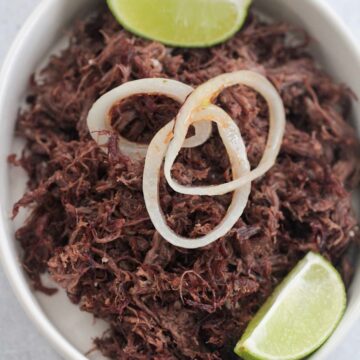 vaca frita with grilled onions and lime wedges.