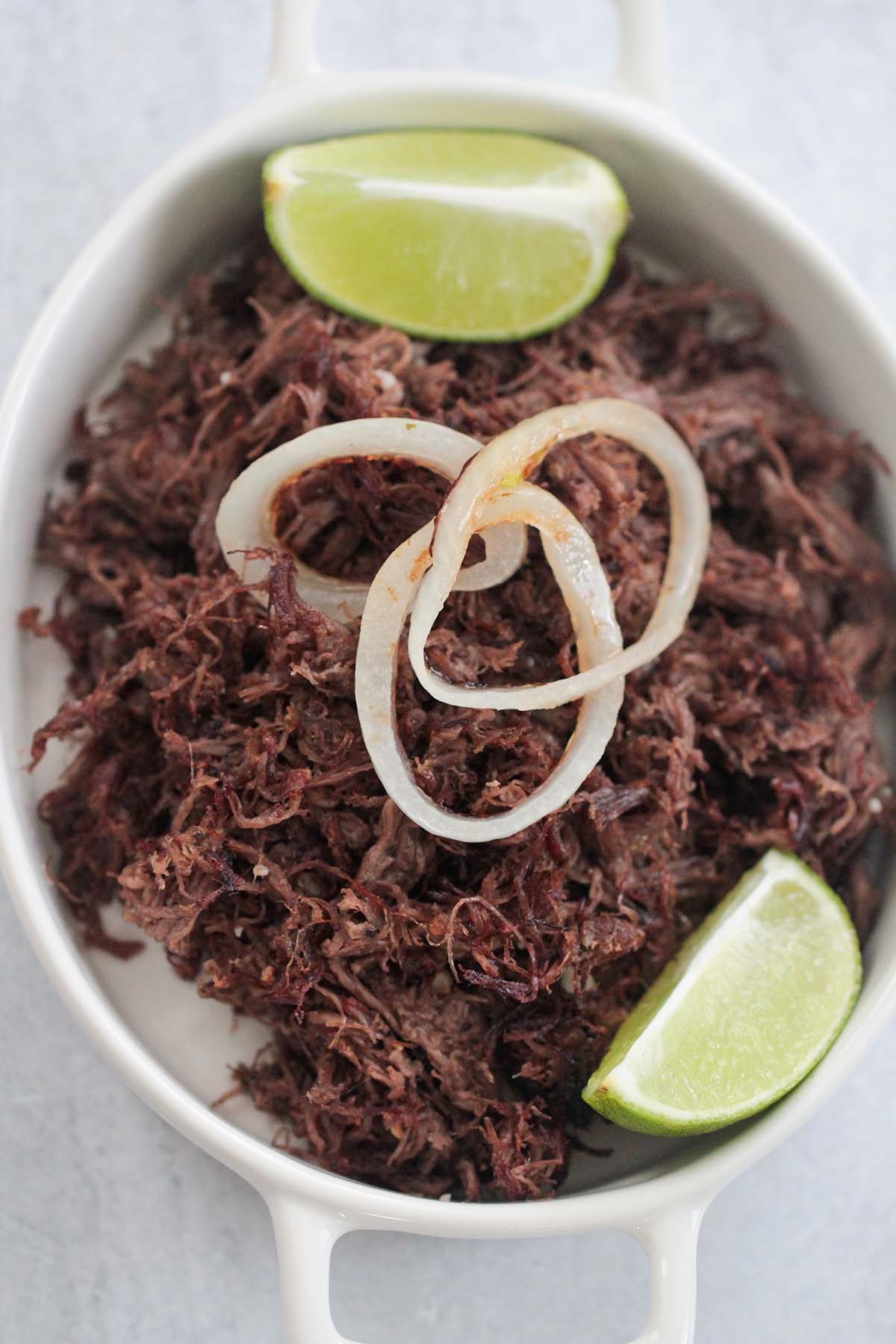 vaca frita with grilled onions and lime wedges. 