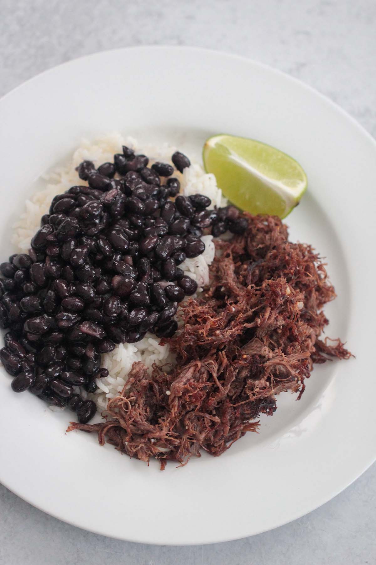 vaca frita with rice, black beans, and a lime wedge. 