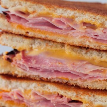 three air fryer grilled ham and cheese sandwiches stacked.