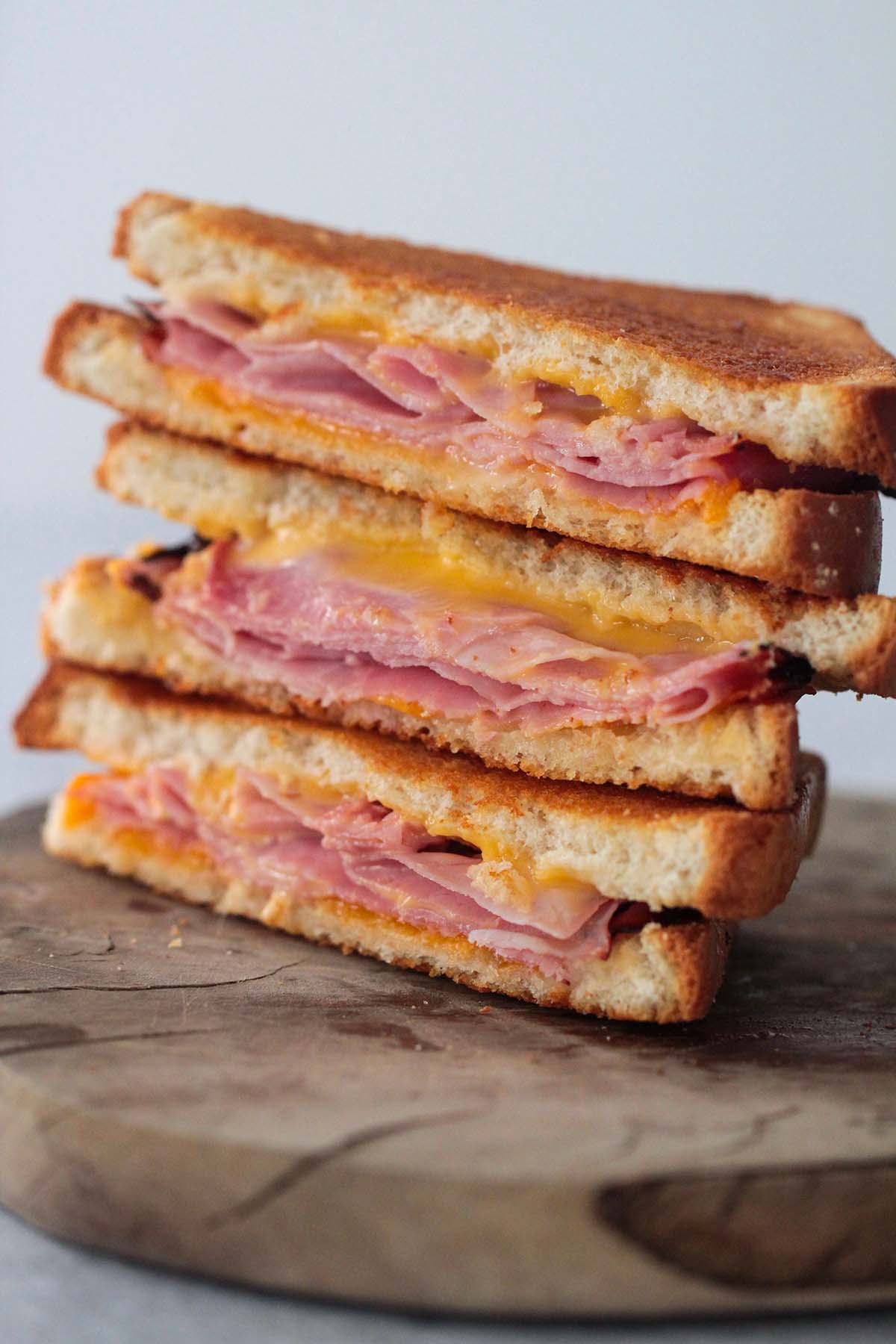 three grilled ham and cheese sandwiches on a cutting board. 