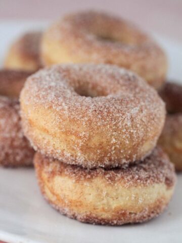 baked cinnamon sugar donuts on a plate up close.