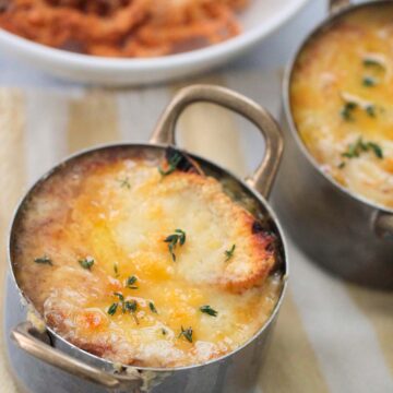 French onions soup with melted cheese and fresh thyme on top.