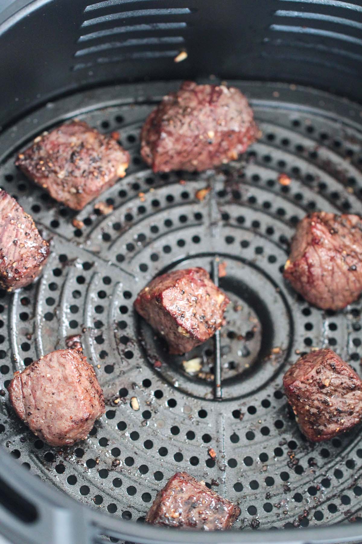 Cooked steak tips in the air fryer basket. 