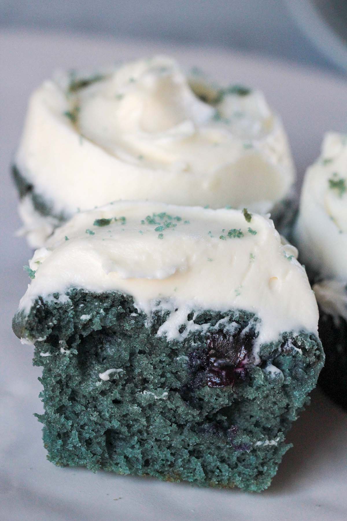 The inside of a blue velvet cupcake with cream cheese frosting. 