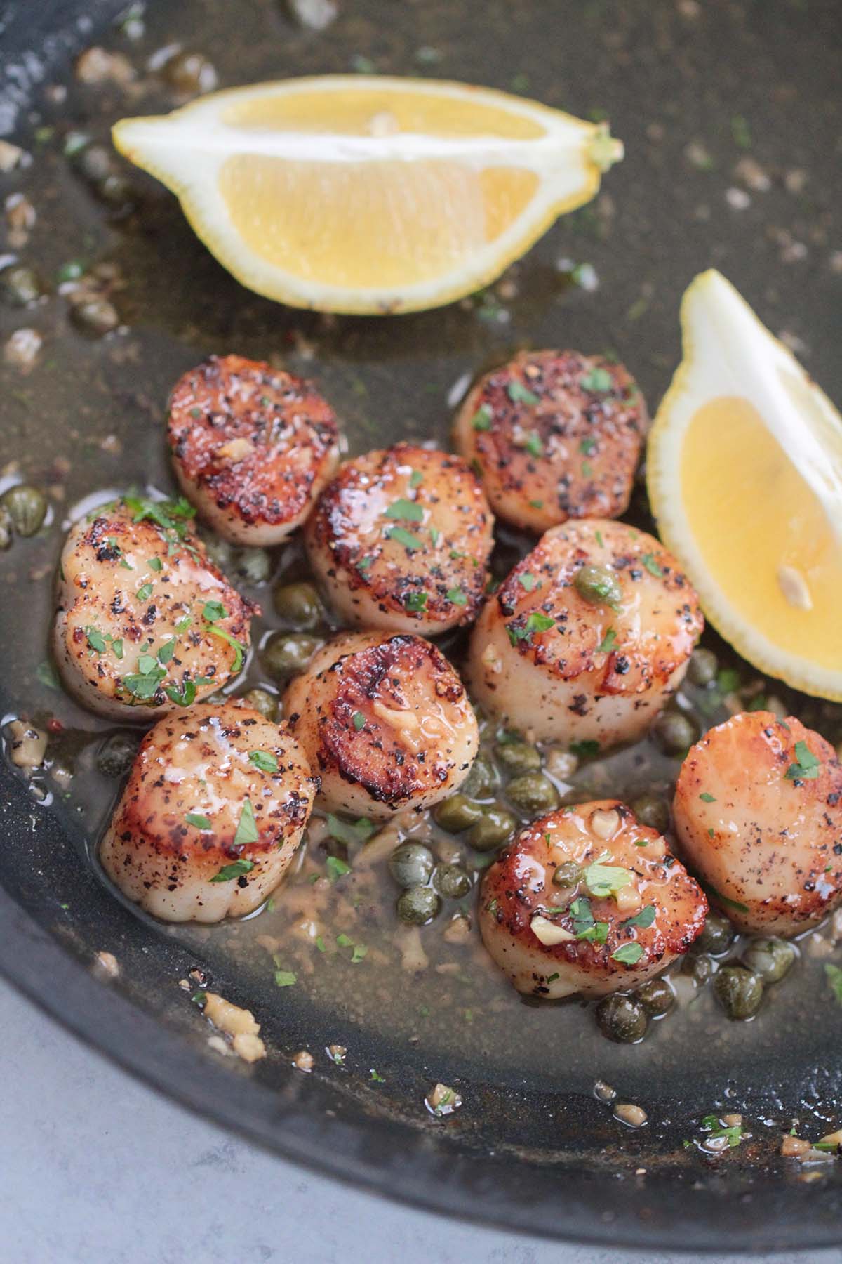pan seared scallops with lemon butter sauce in a skillet. 