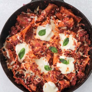 skillet lasagna with melted cheese and fresh basil on top.