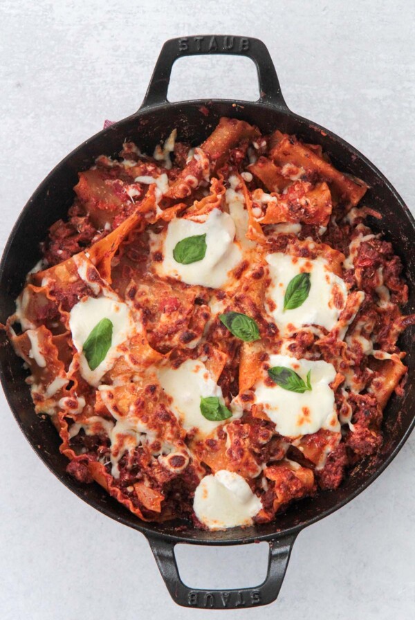 skillet lasagna with melted cheese and fresh basil on top.