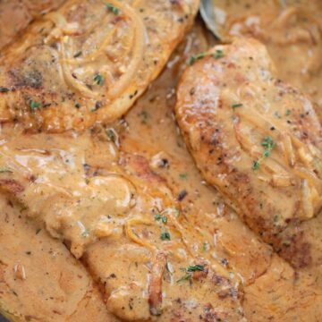 smothered chicken breasts in a skillet.