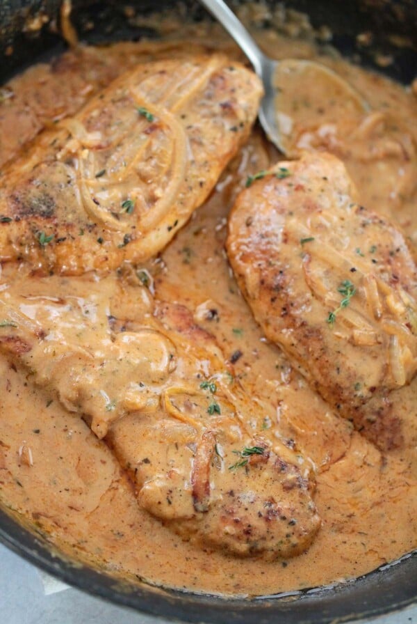smothered chicken breasts in a skillet.