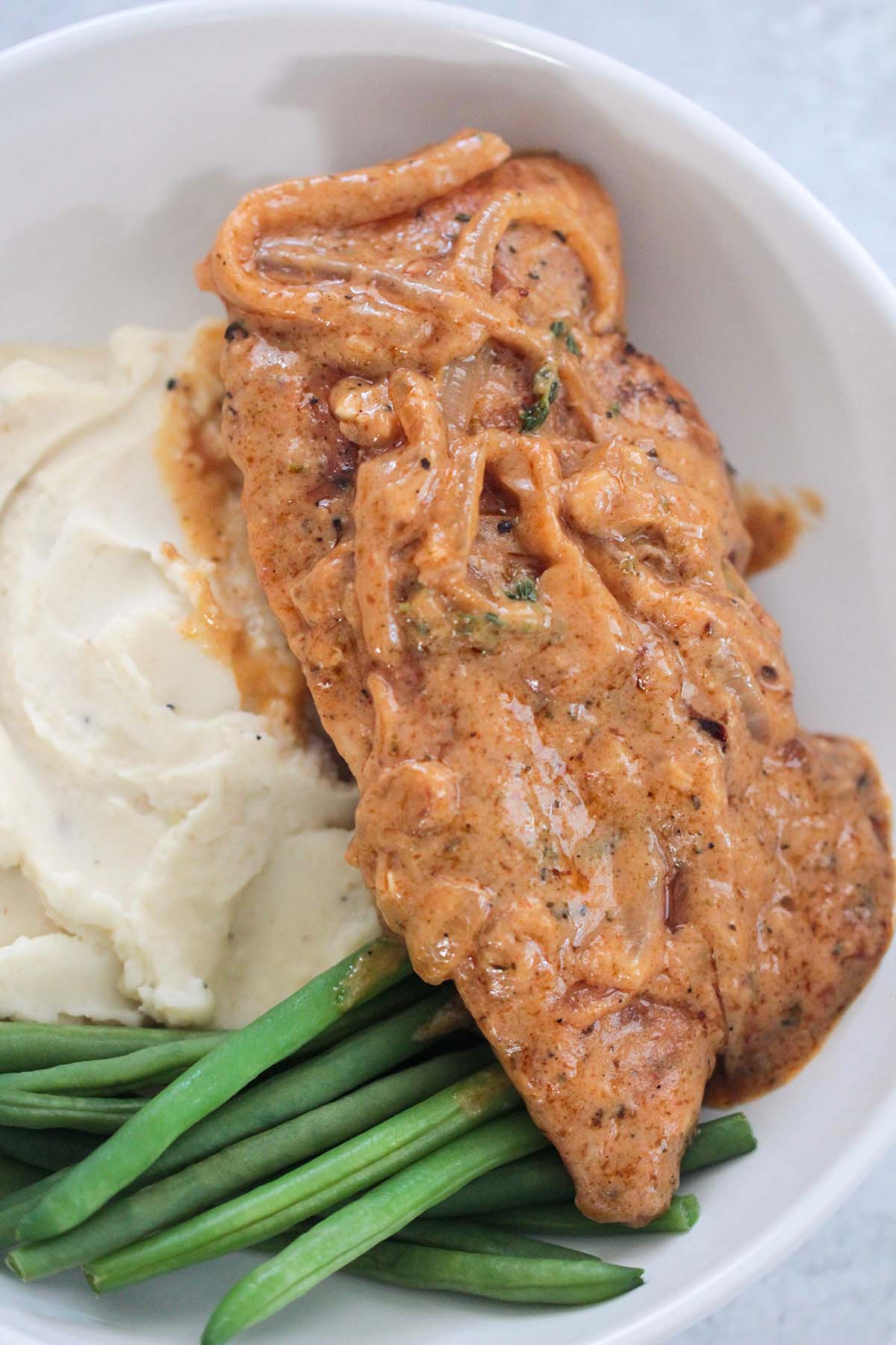 smothered chicken breasts with mashed potatoes and green beans. 