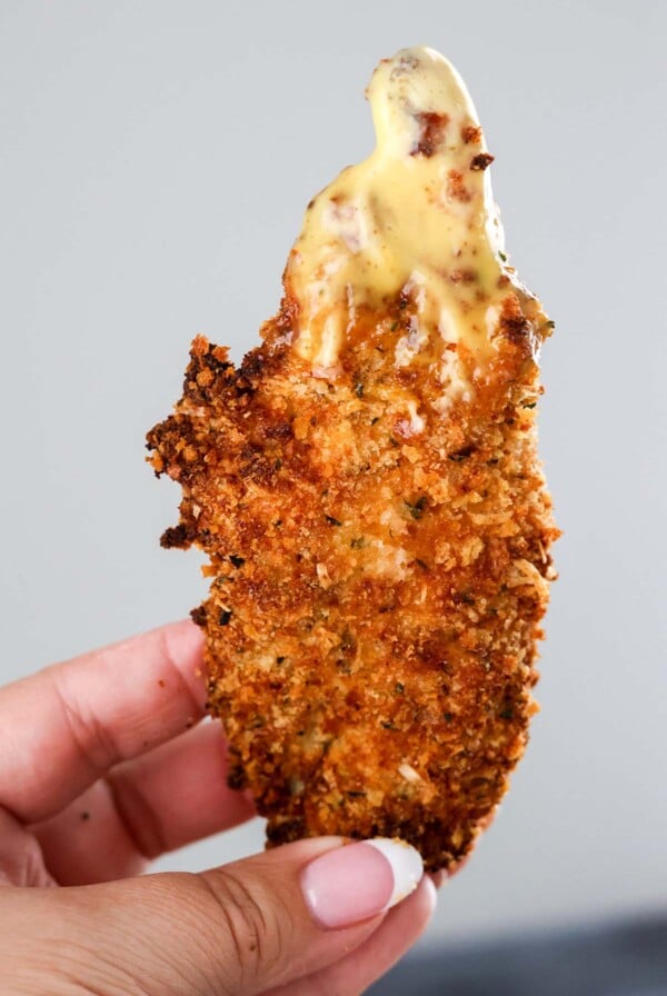 hand held air fryer chicken tender with honey mustard.