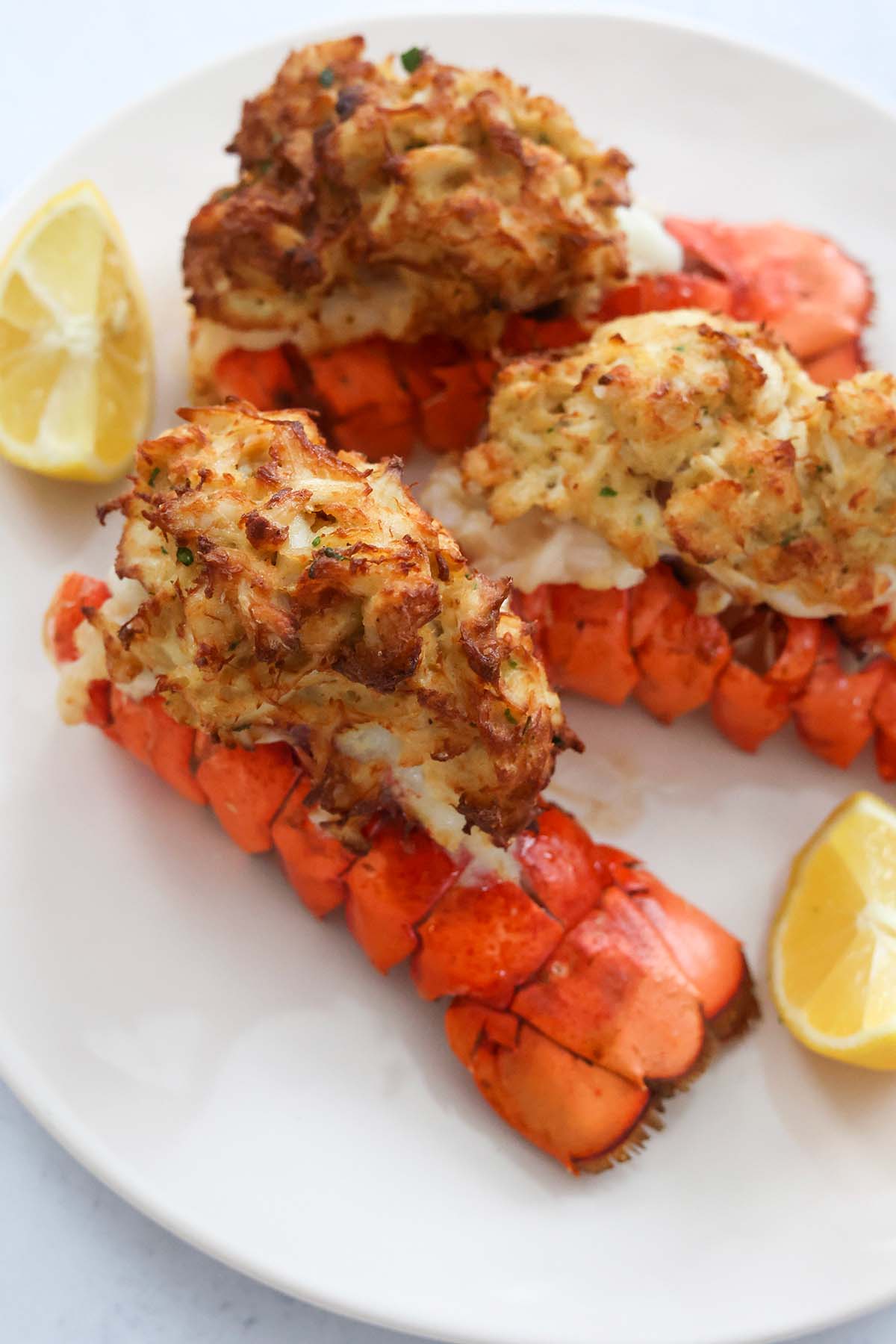three air fryer stuffed lobster tails on a white plate. 