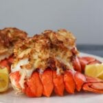 air fryer stuffed lobster tails on a plate with lemon wedges.