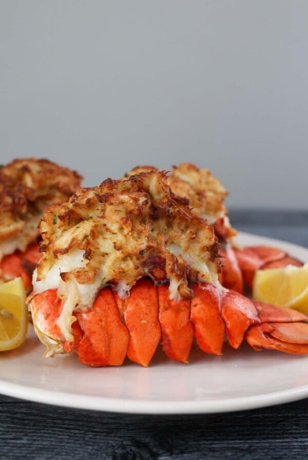 air fryer stuffed lobster tails on a plate with lemon wedges.