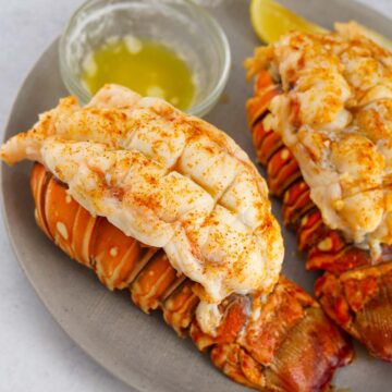 two broiled lobster tails with melted butter on the side.