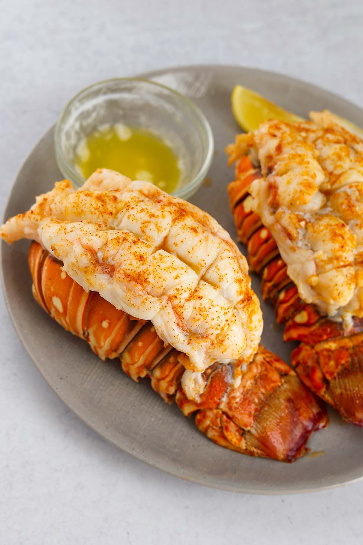 two broiled lobster tails with melted butter on the side. 