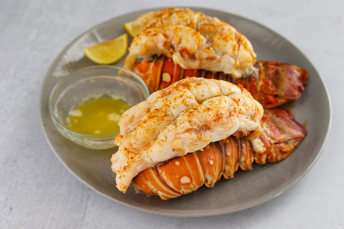 two broiled lobster tails with lemon and melted butter on the side. 