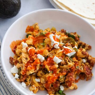 chorizo scrambled eggs with cheese and hot sauce on top.