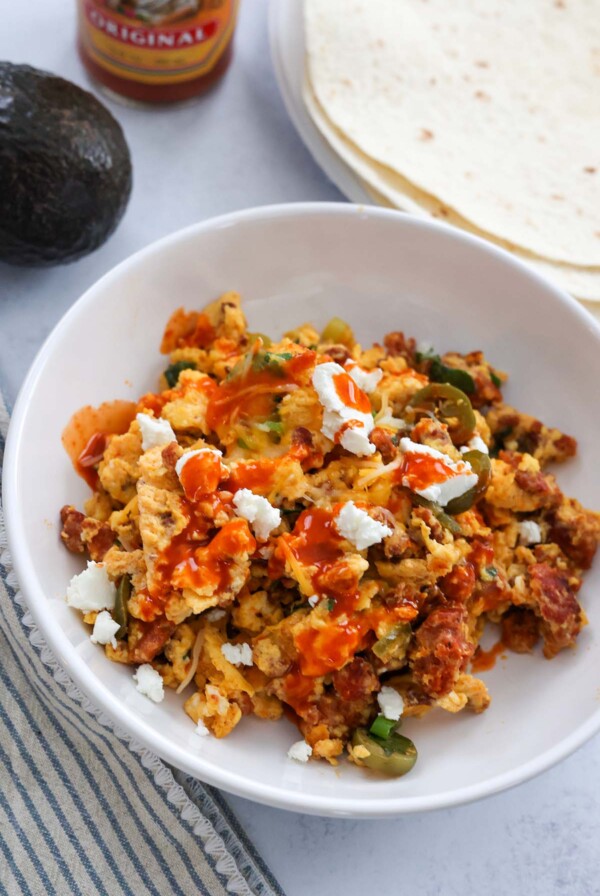 chorizo scrambled eggs with cheese and hot sauce on top.
