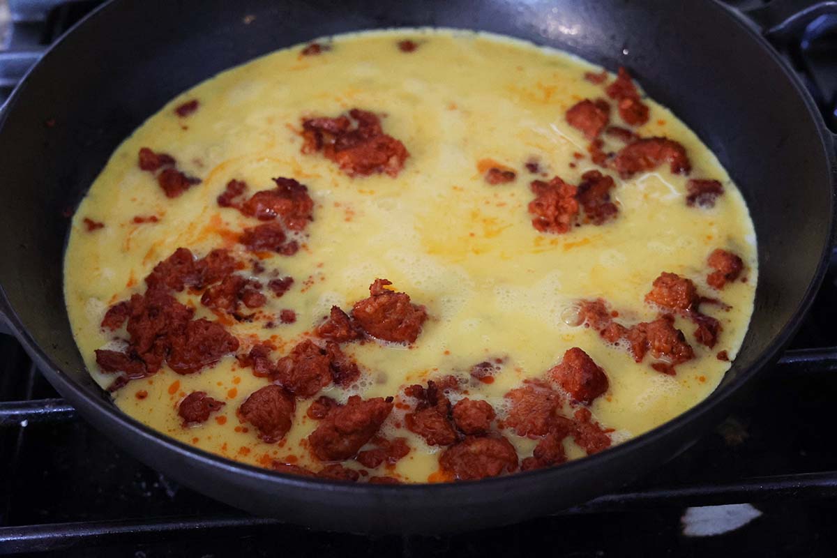chorizo and eggs in a skillet cooking. 