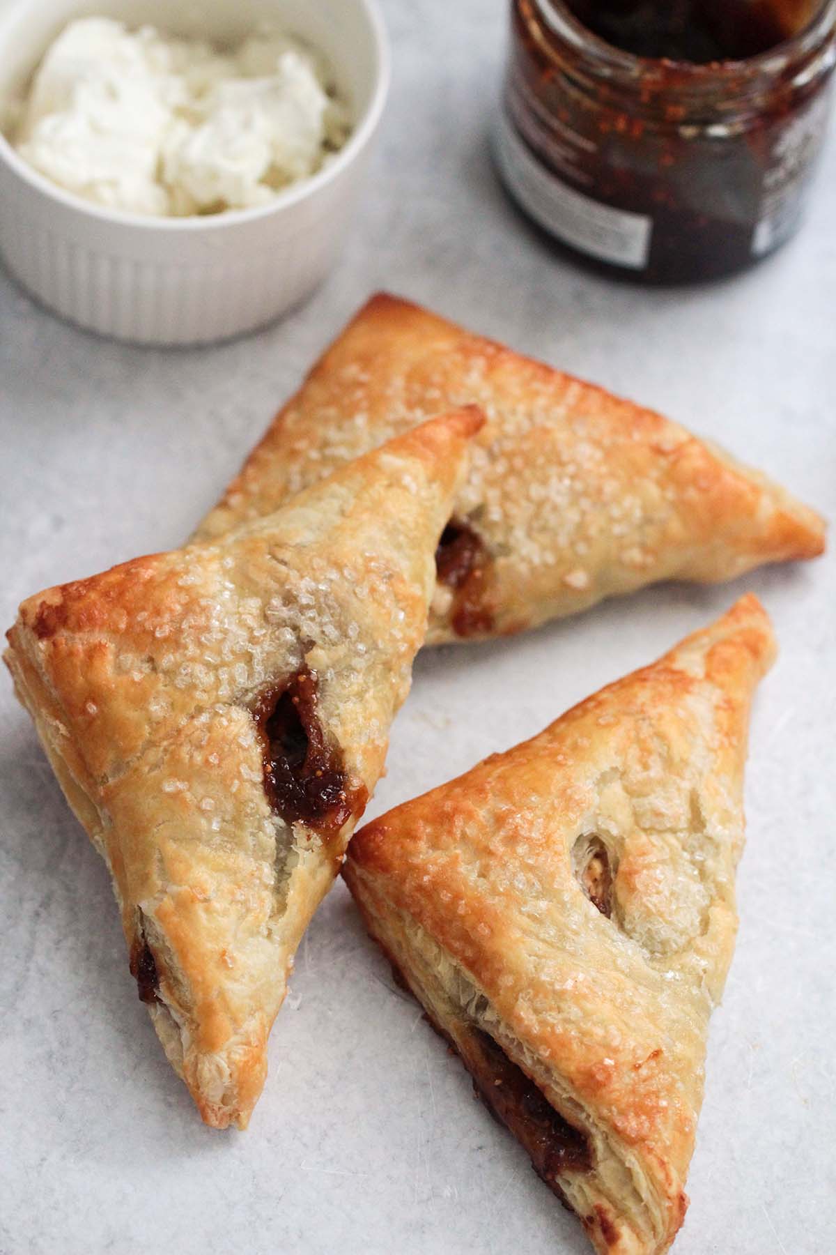 three fig and goat cheese turnovers with goat cheese and fig in the background. 