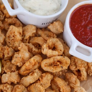 fried calamari with a lemon wedge, marinara sauce, and tartar sauce on the side.