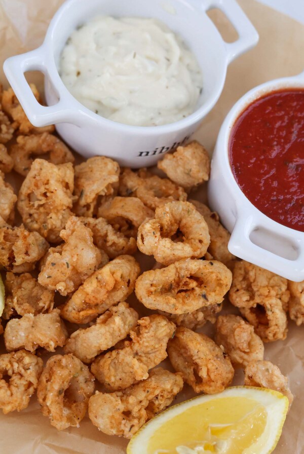 fried calamari with a lemon wedge, marinara sauce, and tartar sauce on the side.