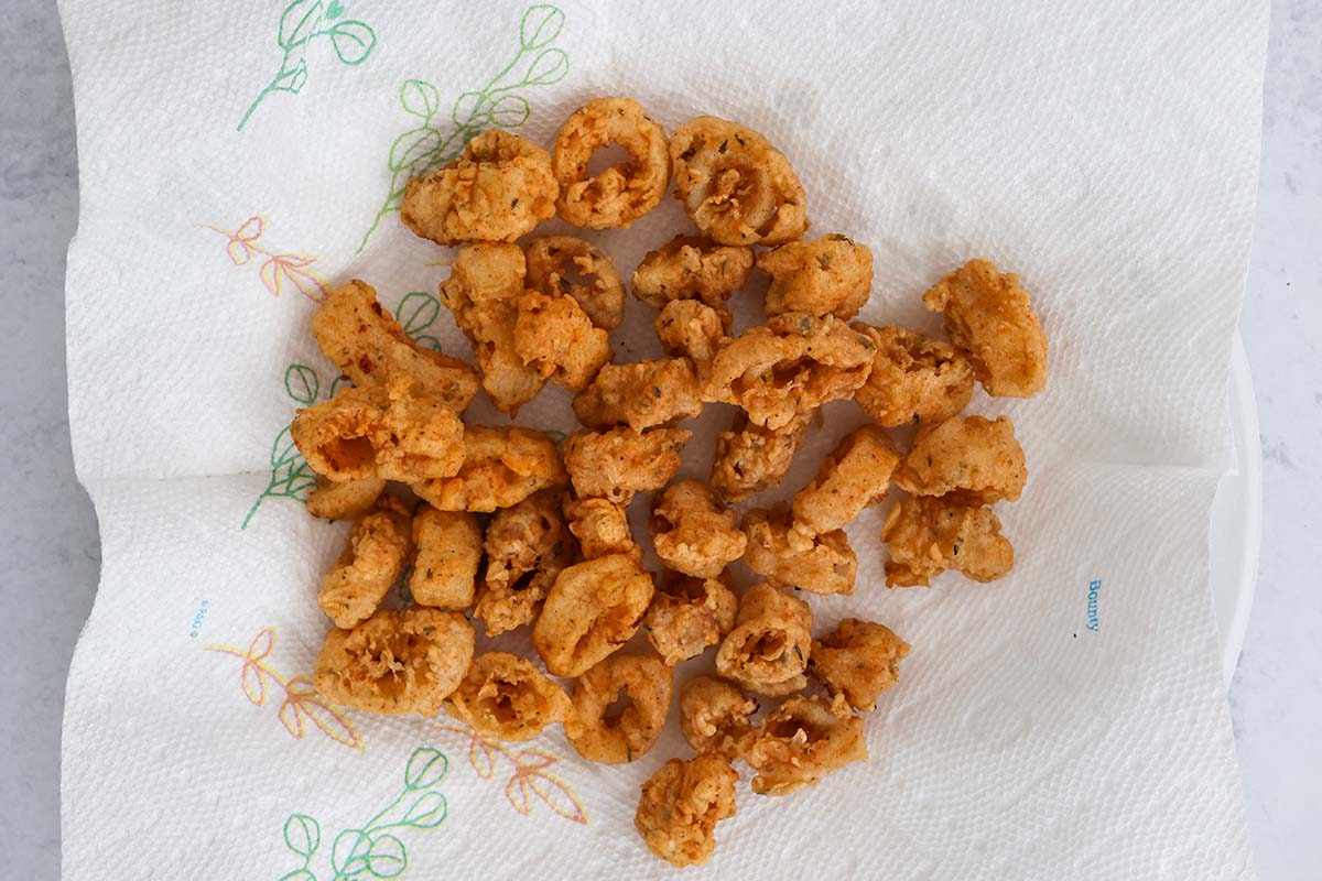 fried calamari on a paper-towel lined plate.