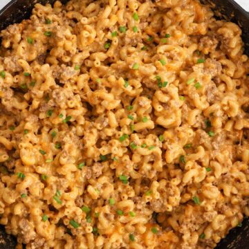 homemade hamburger helper in a black skillet with chives on top.