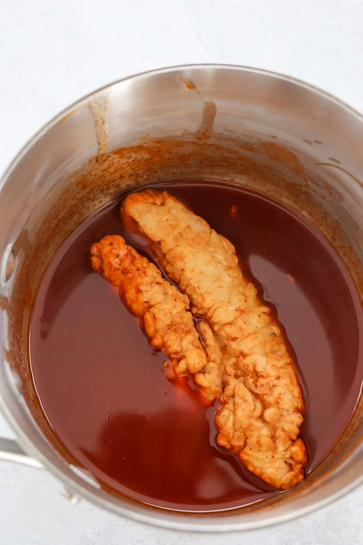 fried chicken tender in a saucepan with sauce. 