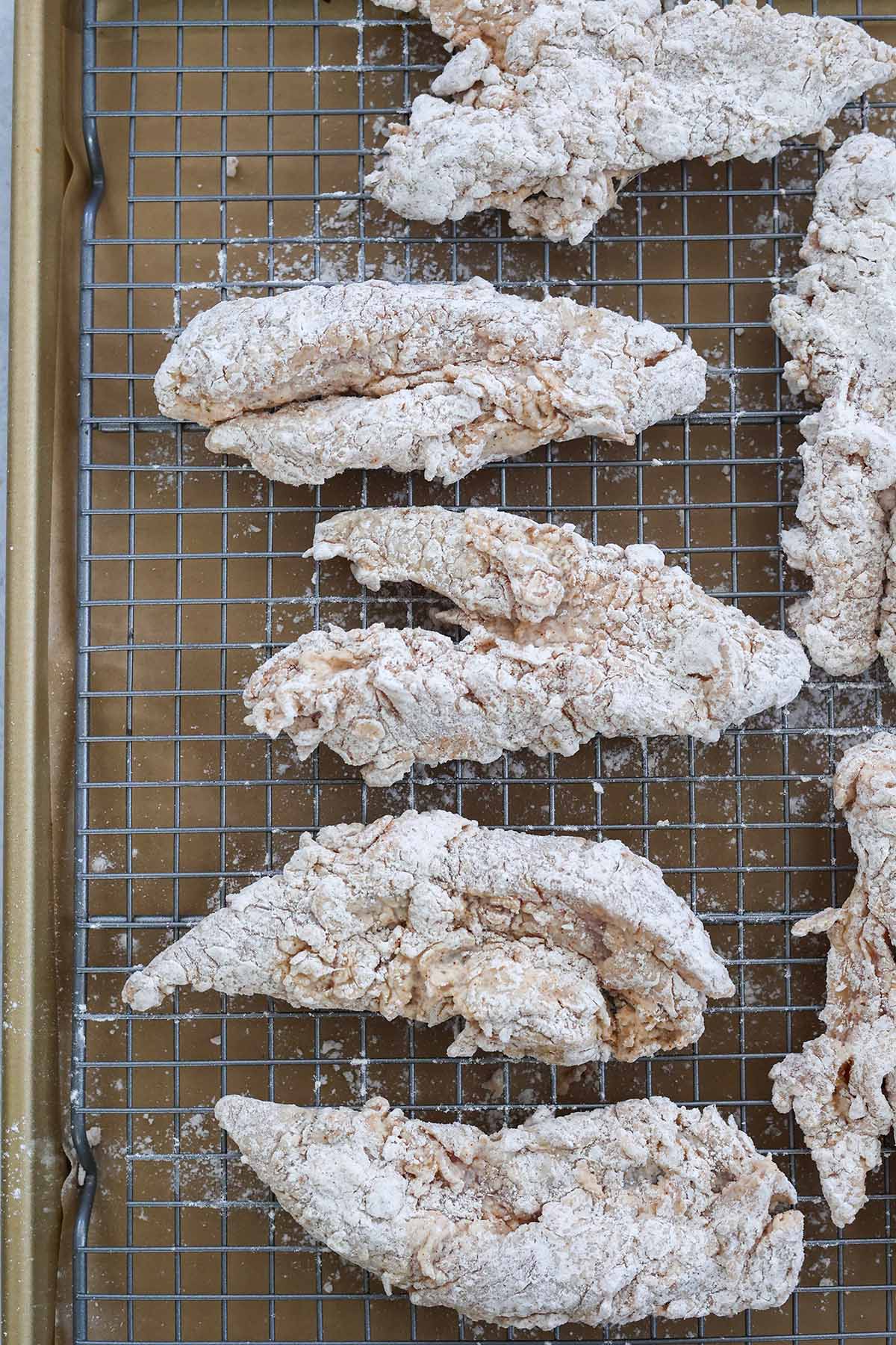 flour coated chicken tenders on a wire rack. 