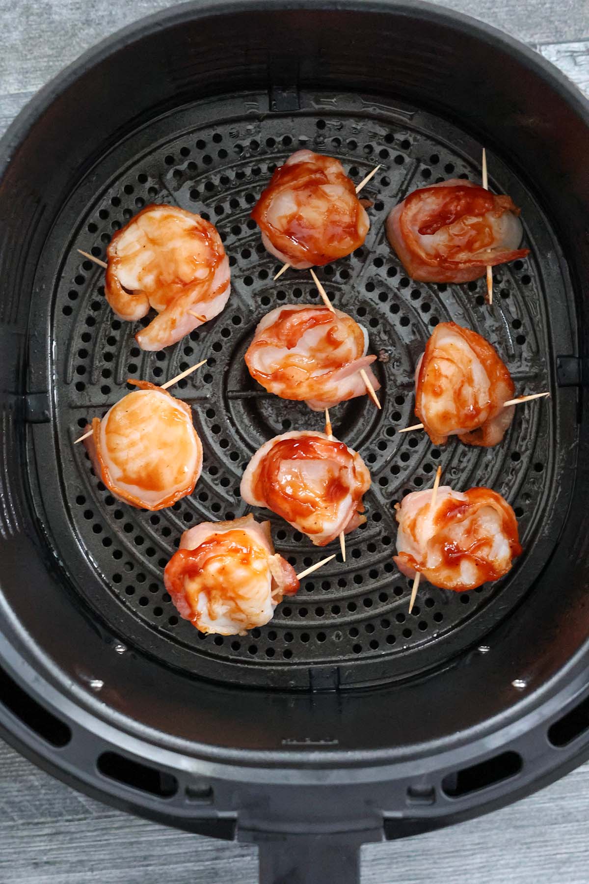 bacon wrapped raw scallops in the air fryer basket. 