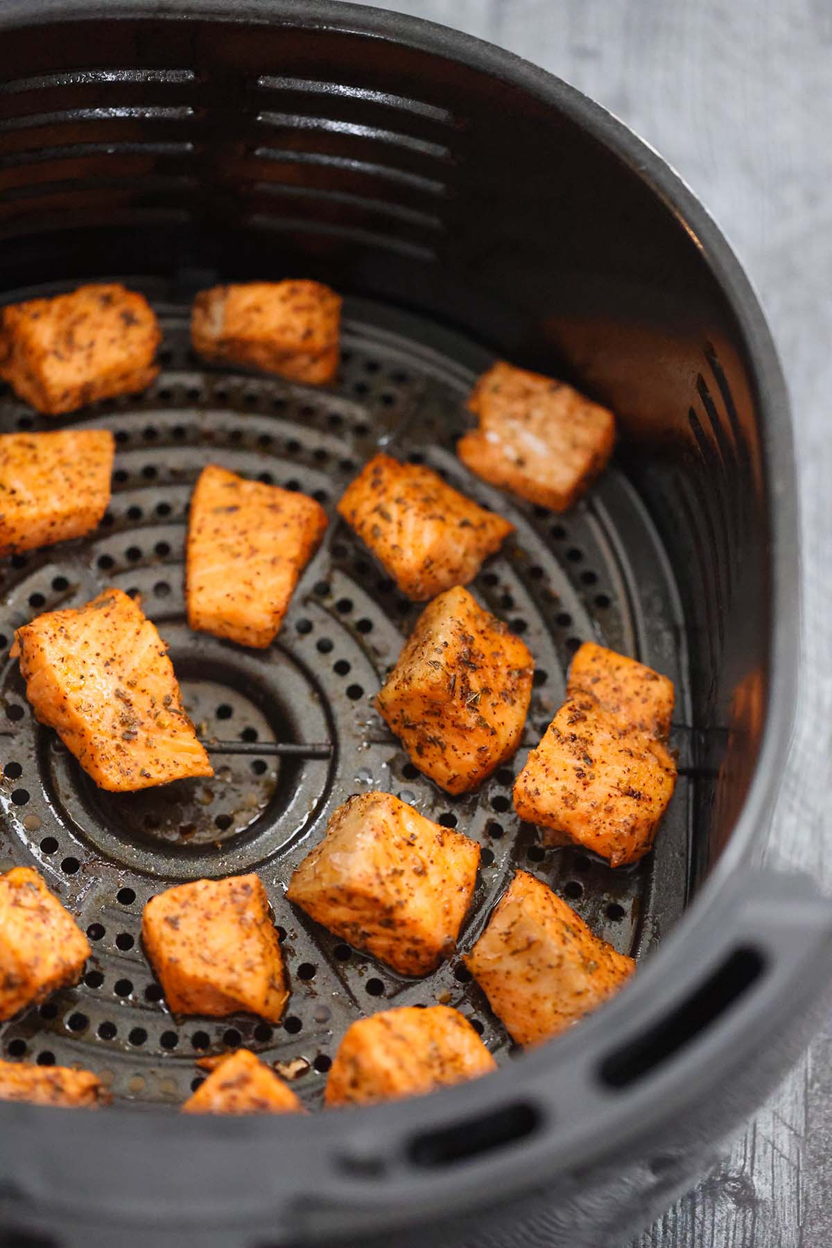 cooked salmon bites in the air fryer basket. 