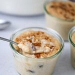 arroz con dulce in a small glass jar with a spoon.