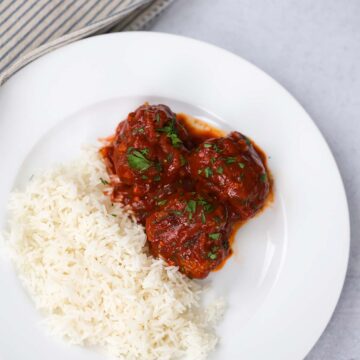 Albondigas with white rice on a white plate.