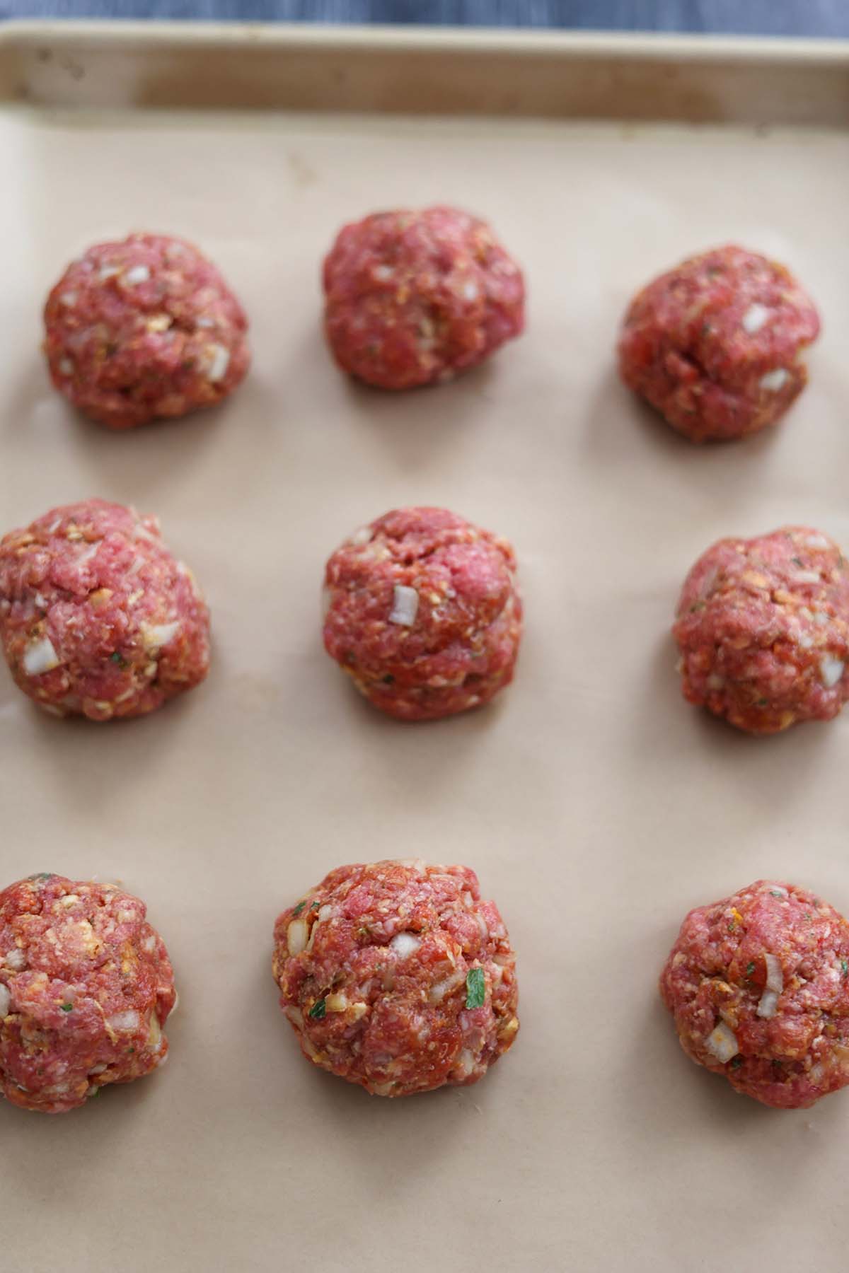 rolled raw meatballs on a baking sheet. 