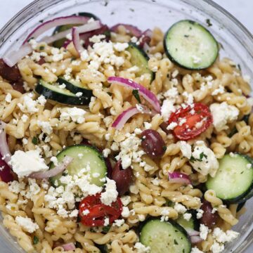 Greek pasta salad in a large glass bowl.