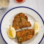 air fryer grouper fillets with lemon wedges, tartar sauce, and hot sauce.