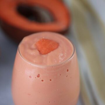 batido de mamey in a glass with a piece of fruit on top.