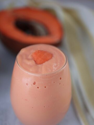 batido de mamey in a glass with a piece of fruit on top.
