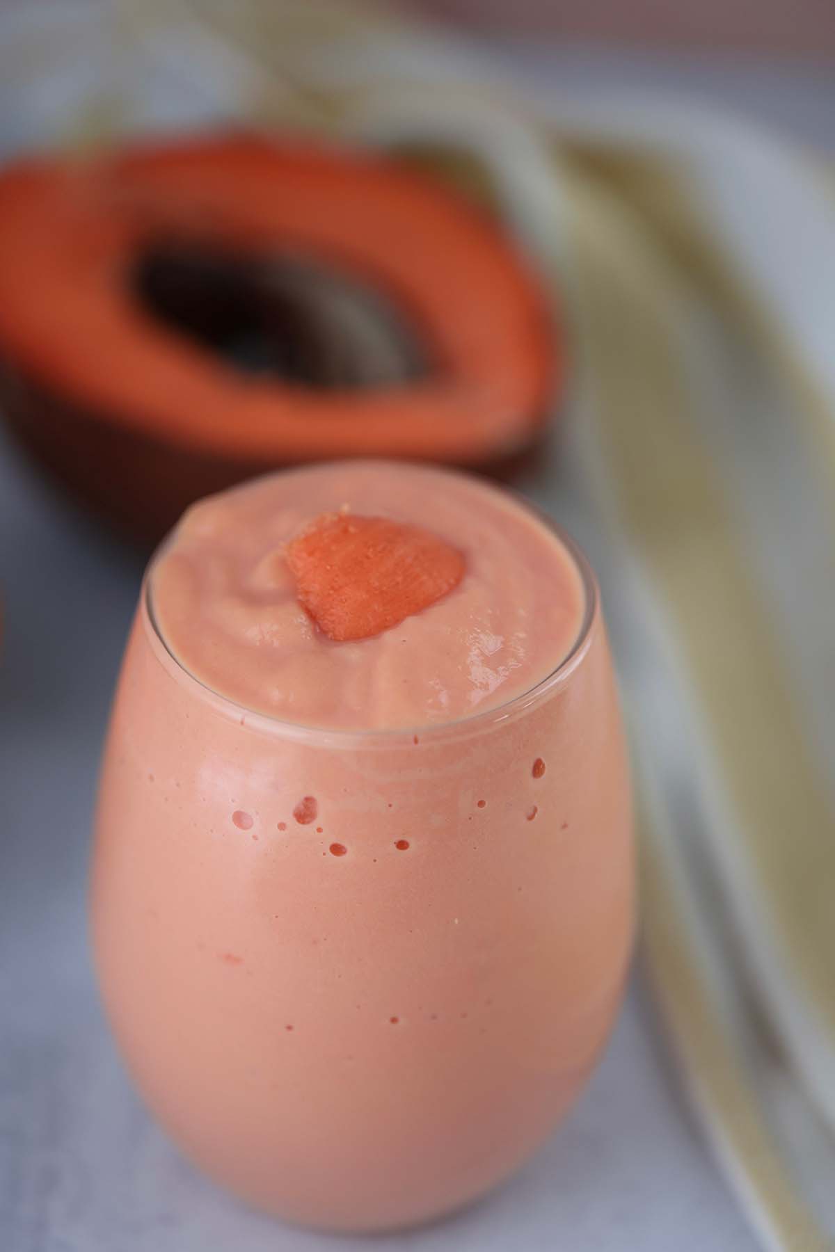 batido de mamey in a glass with a piece of fruit on top. 
