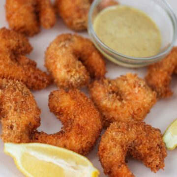 crunchy panko shrimp with lemon wedges and sauce on the side.
