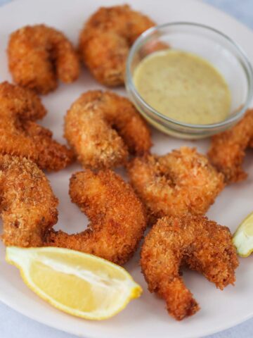 crunchy panko shrimp with lemon wedges and sauce on the side.
