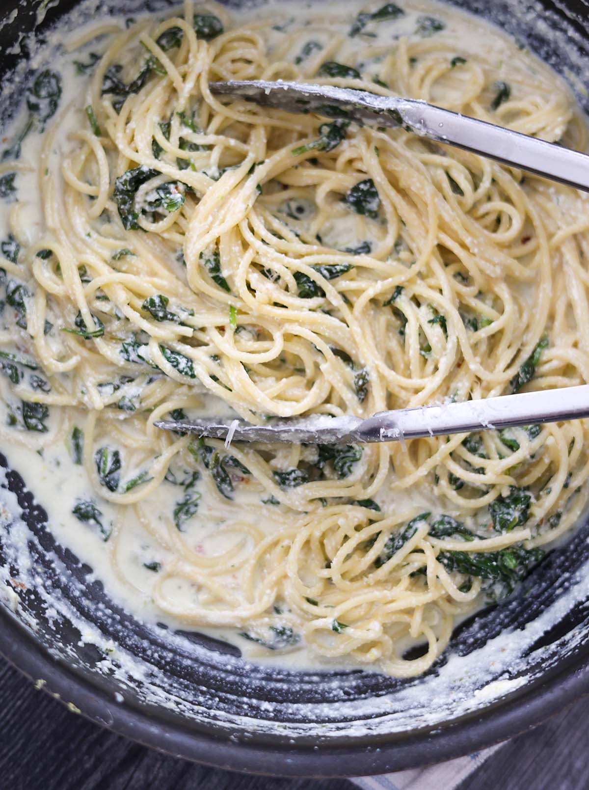 lemon ricotta spaghetti in a skillet with tongs. 