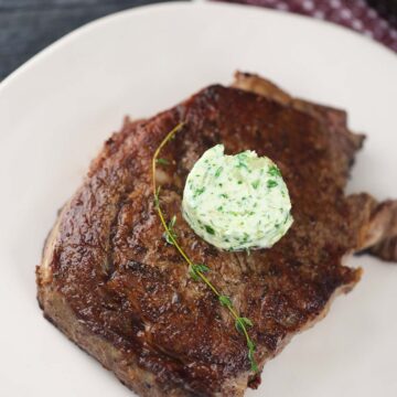 pan-seared ribeye steak with butter and thyme on top.